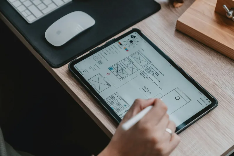 タブレットに、アプリの画面の下絵を描いている手の写真