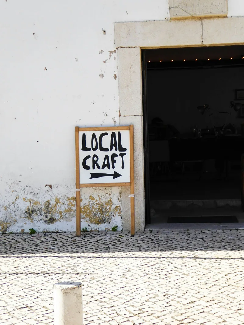 白い壁の前に立つ、「LOCAL CRAFT」と矢印が書かれた小さな看板の写真