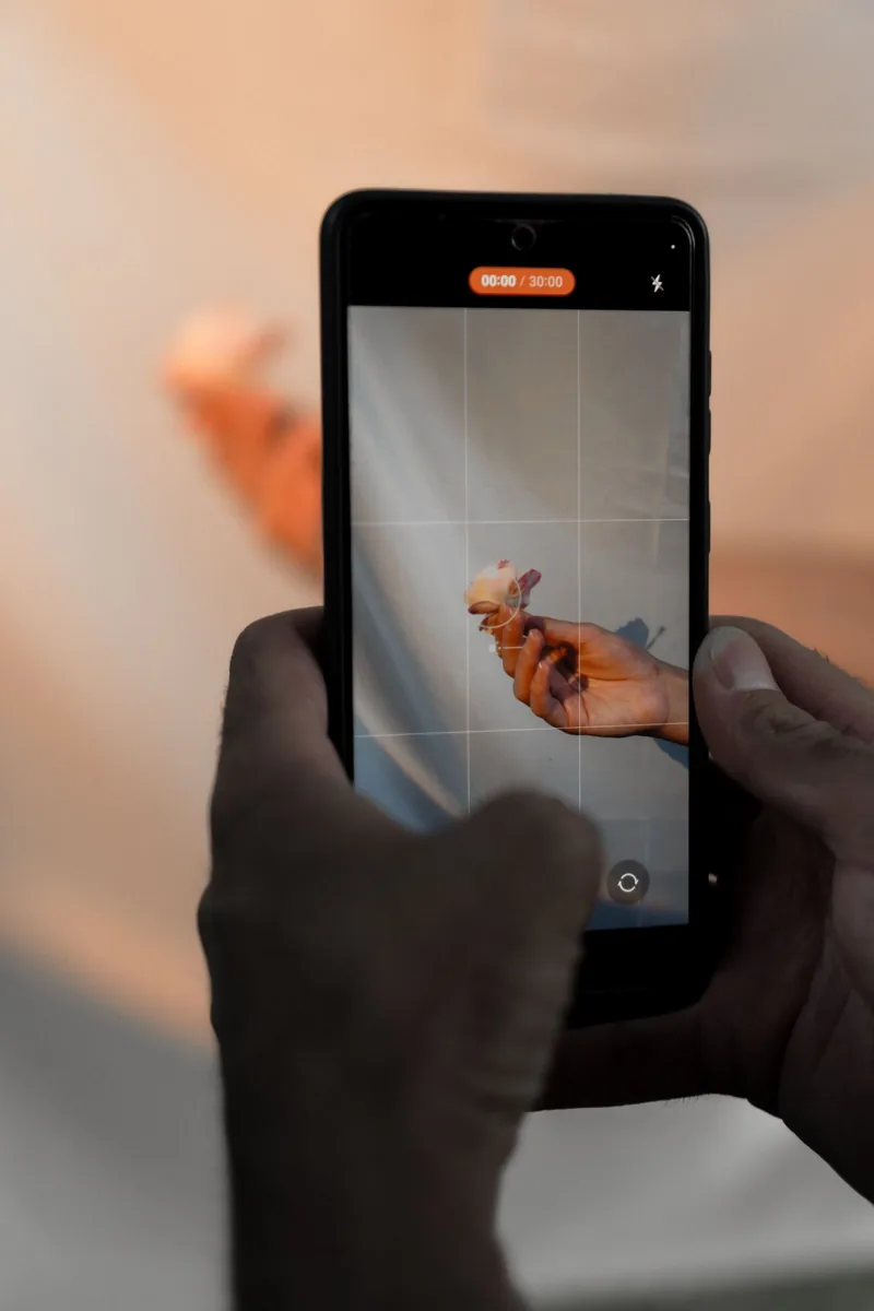 iPhone を片手で持って動画を撮影している手元。三脚を使わず iPhone だけで広告動画を撮るイメージ