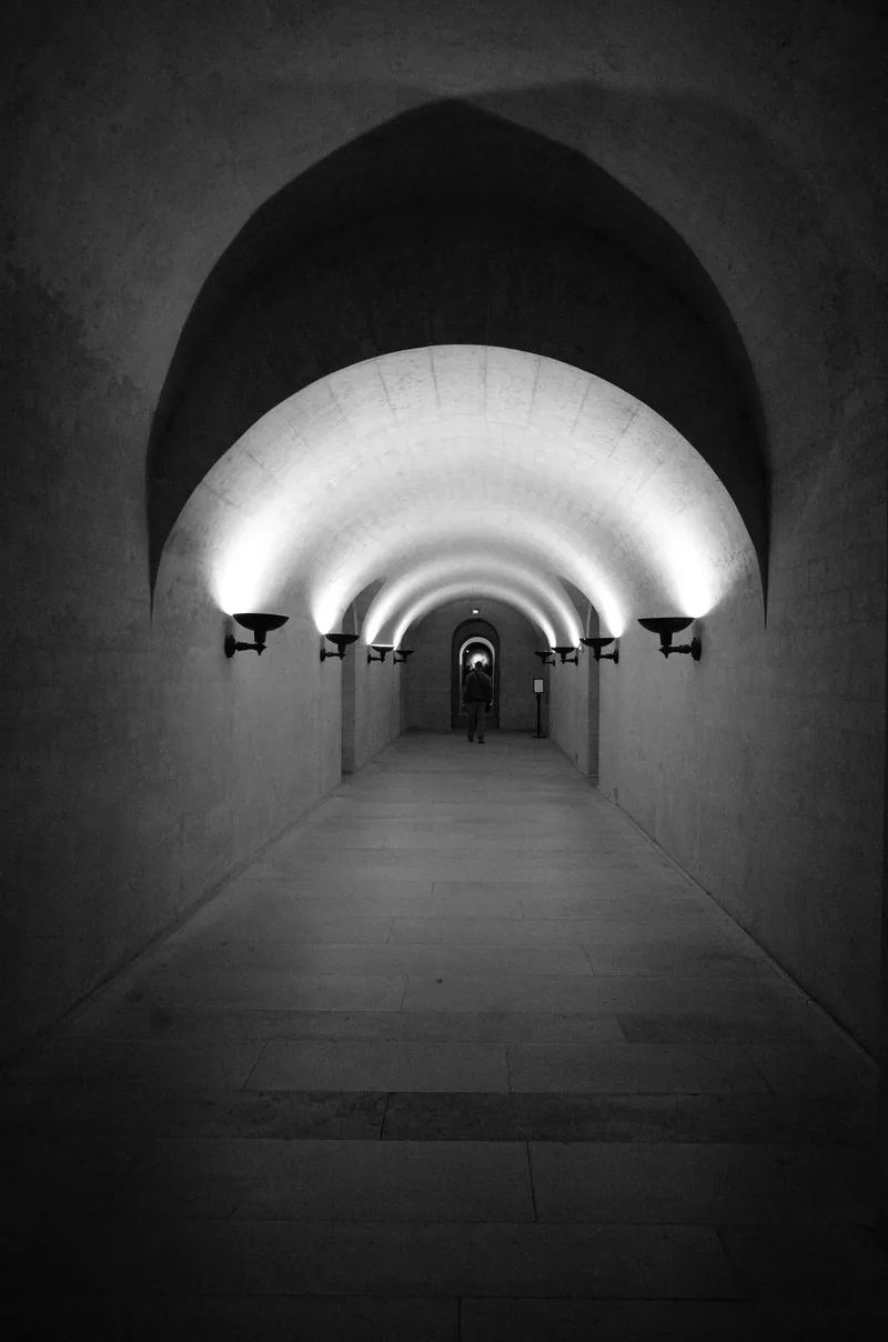 アーチ形の通路の先に、光が見えるトンネルの写真
